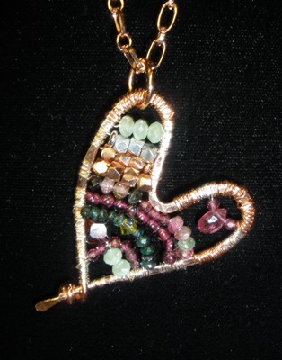 Hammered copper heart with ruby, garnet, emerald, crystal, fine silver.